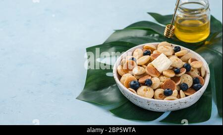 Trendige Speisen - Pfannkuchen Müsli. Haufen Mini-Cereal-Pfannkuchen in Boule auf blauem Hintergrund. Kopieren Sie den für Text übrig gebliebenen Platz. Banner Stockfoto