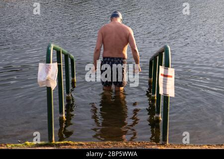 Ein Schwimmer nimmt ein frühes Morgenbad im Serpentine Lido im Hyde Park, London, da es nach der Lockerung der Coronavirus-Lockdown-Maßnahmen für Mitglieder des Serpentine Swimming Club wieder geöffnet wird. Stockfoto