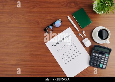 Kalender, Taschenrechner, Tasse Kaffee in Stron Black und Ohrhörer auf dem Bürotisch, Ansicht von oben Stockfoto
