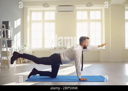 Geschäftsmann tun Yoga-Übungen, während im Büro liegen. Stockfoto