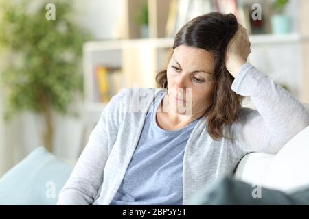 Traurig nachdenkliche Frau mittleren Alters denken, unten sitzend auf einer Couch zu Hause zu sehen Stockfoto