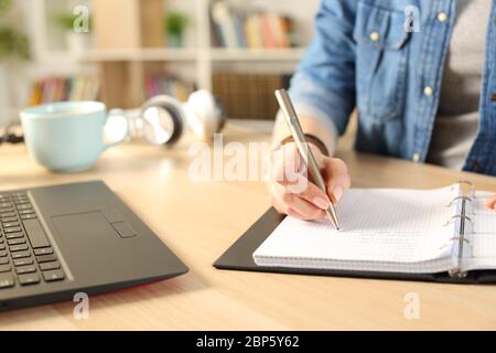 Nahaufnahme von Student Mädchen Hände Schreiben auf Notebook auf einem Schreibtisch zu Hause Stockfoto