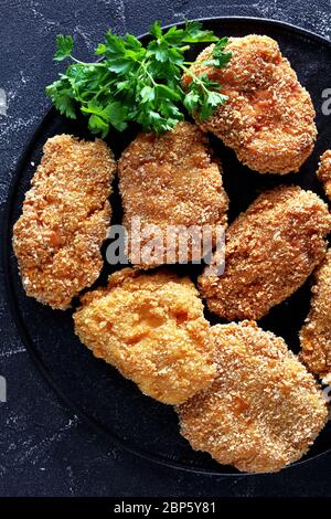 Nahaufnahme japanischer Schweinekotelette, HireKatsu auf schwarzer Platte auf einem Betontisch, horizontale Ansicht von oben, flaches Lay, Makro Stockfoto