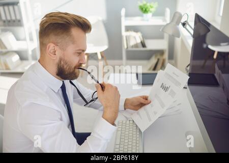 Geschäftsmann in einem weißen Hemd mit Brille. Sehr voll in einem hellen, modernen Büro. Stockfoto