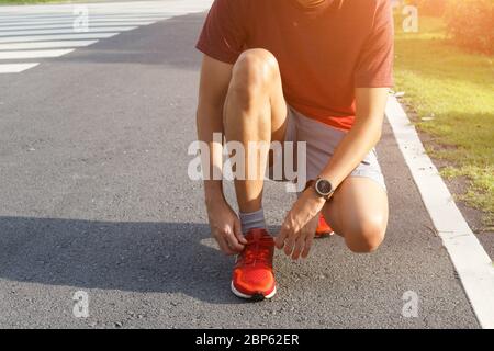 Nahaufnahme des Sportlers im Tunnelpark vor dem Training bindet er Sneaker an Laufschuhe. Laufkonzept. Stockfoto