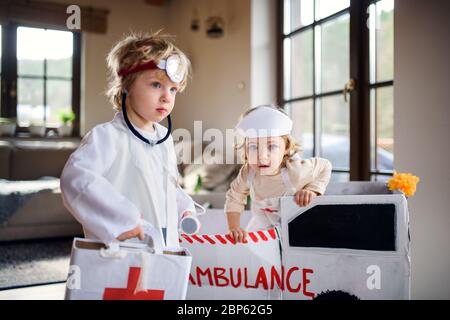 Zwei kleine Kinder mit Arztuniformen zuhause, spielend. Stockfoto