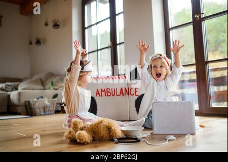 Zwei kleine Kinder mit Arztuniformen zuhause, Spaß beim Spielen. Stockfoto