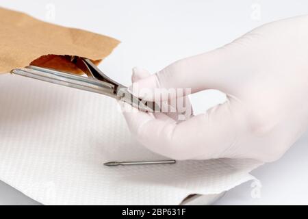 Nahaufnahme der Manikuristin Hand, die das Maniküre-Werkzeug aus dem Papierumschlag herausnimmt. Stockfoto