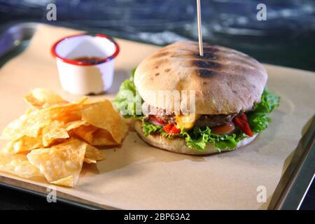 Burger mit Fleisch und Gemüse. Doppelter Käseburger. Heißer Burger in einer brennenden Sauce. Stockfoto