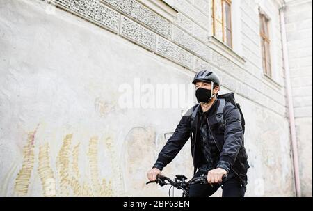 Lieferung Mann Kurier mit Gesichtsmaske und Fahrrad Radfahren in der Stadt. Stockfoto