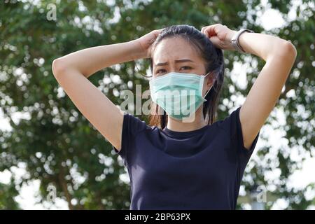 Junge asiatische Frau in medizinischen Schutzmaske tun Stretching Warmup vor der Übung am Morgen.Workout im Freien. Konzept der gesunden Stockfoto