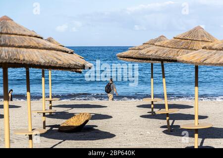 Die Menschen flüchten zwischen den unbenutzten Sonnenschirmen, die während der ersten Phase der Deeskalation des Covid 1 am Strand von Playa Fanabe Sport treiben Stockfoto