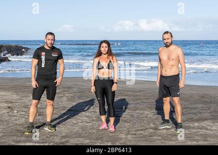 Drei junge Menschen posieren für ein Porträt, während sie während der ersten Phase der Deeskalation des Covid 19 am Strand Playa Fanabe körperliche Distanz wahren, Stockfoto