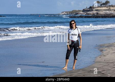 Junge Kanarierin, die am Strand Playa Fanabe in der ersten Phase der Deeskalation des Covid 19 am Strand entlang spazierend, Coronavirus, Notstand, Stockfoto
