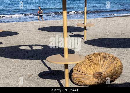 Die Menschen flüchten zwischen den unbenutzten Sonnenschirmen, die während der ersten Phase der Deeskalation des Covid 1 am Strand von Playa Fanabe Sport treiben Stockfoto