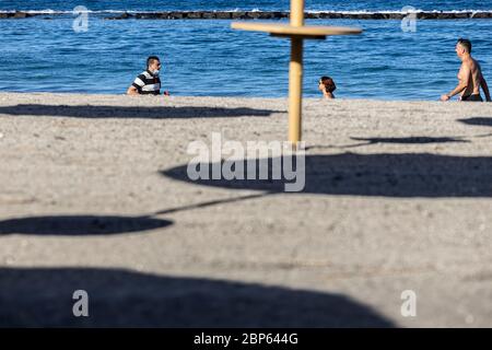 Die Menschen flüchten zwischen den unbenutzten Sonnenschirmen, die während der ersten Phase der Deeskalation des Covid 1 am Strand von Playa Fanabe Sport treiben Stockfoto