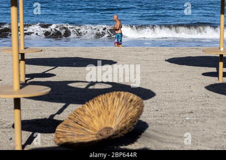 Die Menschen flüchten zwischen den unbenutzten Sonnenschirmen, die während der ersten Phase der Deeskalation des Covid 1 am Strand von Playa Fanabe Sport treiben Stockfoto