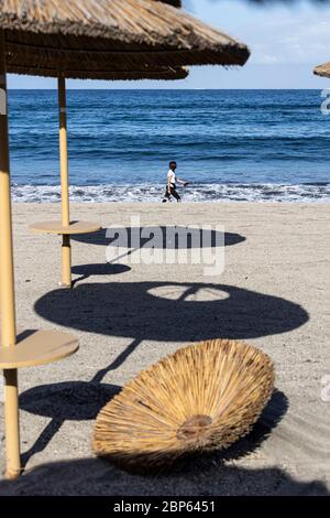 Die Menschen flüchten zwischen den unbenutzten Sonnenschirmen, die während der ersten Phase der Deeskalation des Covid 1 am Strand von Playa Fanabe Sport treiben Stockfoto