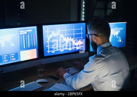 Geschäftsmann mit Computer am Schreibtisch, der spät arbeitet. Konzept der Finanzkrise. Stockfoto