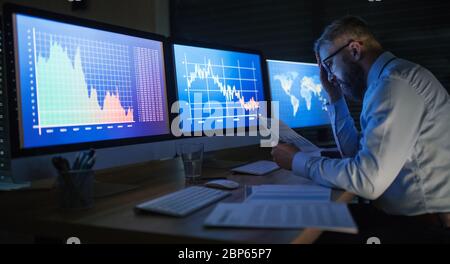 Frustrierter Geschäftsmann mit Computer an der Rezeption, der spät arbeitete. Konzept der Finanzkrise. Stockfoto