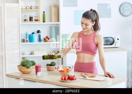 Taille up Porträt von fit junge Frau Gießen Olivenöl in Salat beim Kochen Fitness-Lebensmittel in der Küche Innenraum, kopieren Raum Stockfoto