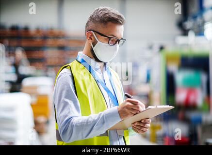 Techniker oder Ingenieur mit Schutzmaske arbeiten in der industriellen Fabrik, Schreiben. Stockfoto