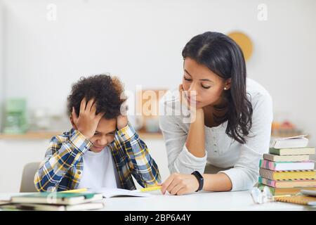 Porträt von Jugendlichen afrikanischen Jungen zu Hause studieren und kämpfen mit Mutter ihm helfen, kopieren Raum Stockfoto