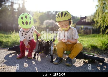 Kleine Kinder mit Gesichtsmasken spielen im Freien mit Fahrrad, Coronavirus Konzept. Stockfoto