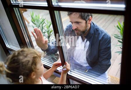 Doktor kommt, um Tochter in der Isolation zu sehen, Fensterglas trennt sie. Stockfoto