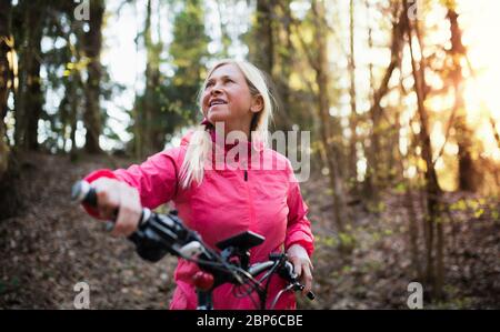 Aktive ältere Frau mit E-Bike Radfahren im Freien in der Natur. Stockfoto