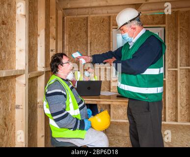 Carrigaline, Cork, Irland. 18. Mai 2020.am ersten Tag der ersten Phase mit der Lockerung der Covid-19 Restriktionen überprüft der Sicherheitsbeauftragte Michael O'Sullivan die Temperierung eines der von Caroline O'Keffee unterstützten Arbeiter auf der Astra-Baustelle in Janeville, Carrigaline, Co. Cork, Irland. - Credit; David Creedon / Alamy Live News Stockfoto