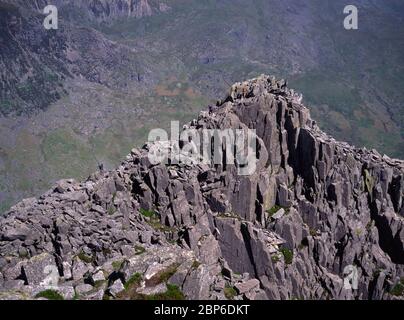 Gruppe von Bergsteigern, die die Gipfelblöcke auf Tryfan in Nordwales, Großbritannien, hinunterfahren Stockfoto