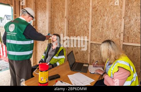 Carrigaline, Cork, Irland. 18. Mai 2020.am ersten Tag der ersten Phase mit der Lockerung der Covid-19 Restriktionen überprüft der Sicherheitsbeauftragte Michael O'Sullivan die Temperierung eines der von Caroline O'Keffee unterstützten Arbeiter auf der Astra-Baustelle in Janeville, Carrigaline, Co. Cork, Irland. - Credit; David Creedon / Alamy Live News Stockfoto