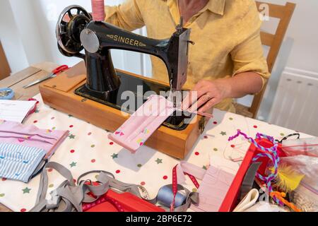 Eine Frau stellt während der Coronavirus-Pandemie 2020 in Großbritannien 19 auf einer alten Singer Nähmaschine hausgemachte Gesichtsmasken her. Stockfoto