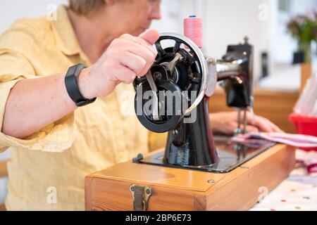 Eine Frau stellt während der Coronavirus-Pandemie 2020 in Großbritannien 19 auf einer alten Singer Nähmaschine hausgemachte Gesichtsmasken her. Stockfoto