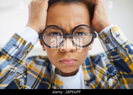 Nahaufnahme von niedlichen afrikanischen Jungen tragen große Brille runzeln und pouting beim Blick auf Kamera Stockfoto