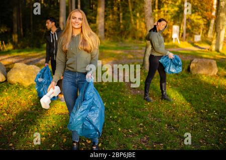 Junge Freiwillige in einem Team hält Müllbeutel im Park Stockfoto