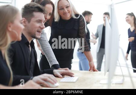 Gruppe junger Mitarbeiter, die auf die Bildschirme von Bürocomputern schauen. Stockfoto