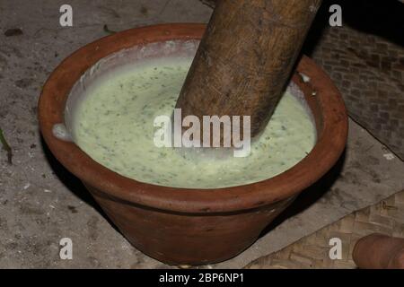 Ein Mann macht Joghurt Sause, die in Indien und Pakistan Raita genannt wird, mit Joghurt, grünem Chili, Zwiebeln, Minze und Koriander gemacht. Stockfoto