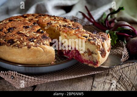 Hausgemachte köstliche Rote Bete Tarte auf Küchengrill mit Scheibe Kuchen und frischen Rote Bete auf rustikalem Holzbackboden. Menü, Tafel, Banner. Traditionelle rustikale Küche. Britische Küche Stockfoto