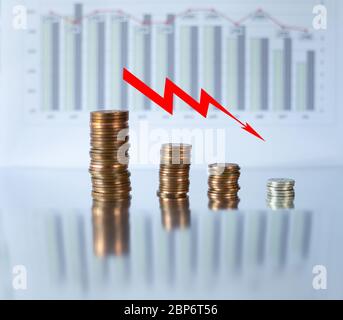 Roter Pfeil nach unten auf dem Hintergrund von Münzen Geld und Grafiken. Konzept der wirtschaftlichen Finanzkrise, Rezession. Rückläufige Trends, die weltweit aufgrund der Coronavirus-Pandemie nach unten gehen Stockfoto