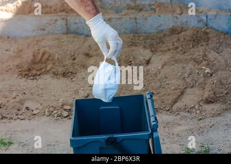 Mann wirft gebrauchte chirurgische Maske in Recycling-Behälter. Abfallentsorgung Problem in Coronavirus Zeiten, covid-19 Stockfoto