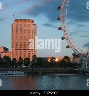 Shell Centre im Juni 2012 (vor der Sanierung) und das ikonische London Eye am Südufer der Themse, das von der spät untergehenden Sonne im Zentrum Londons, Großbritannien, beleuchtet wird. Stockfoto