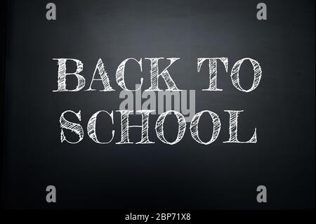 ZURÜCK IN DIE SCHULE, weißer Titel mit Kreide auf schwarzem Schulbrett geschrieben. Stockfoto