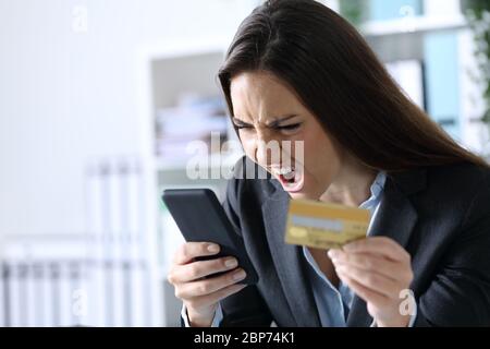 Wütende Exekutive Frau schreit Online bezahlen auf Smartphone mit Kreditkarte im Büro sitzen Stockfoto