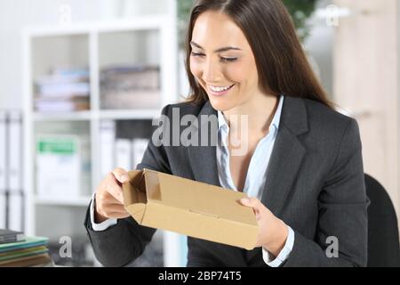 Glückliche Exekutive Frau Eröffnung Paket Lieferung sitzt auf einem Schreibtisch im Büro Stockfoto