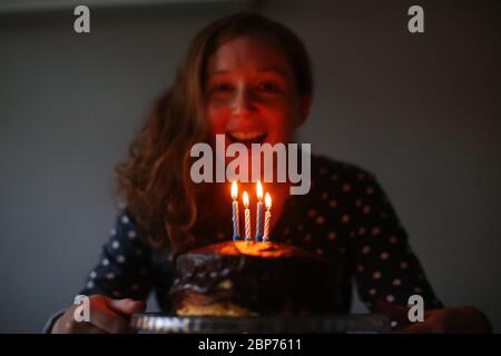 Eine Frau feiert ihren Geburtstag, indem sie die Kerzen auf ihrer Geburtstagstorte in Belfast, Nordirland, ausbläst. Stockfoto