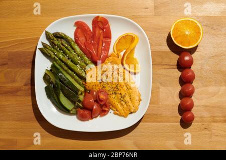 Lachsfilet in Orangensauce mit Kirschtomaten, Zucchini, Spargel, rotem Pfeffer und Basilikum und Hanfsamen. Stockfoto