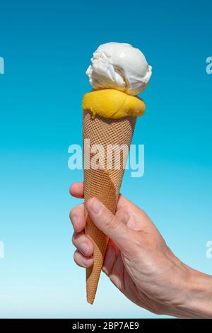 Hand hält einen Eiscreme-Kegel auf blauem Himmel Hintergrund Stockfoto