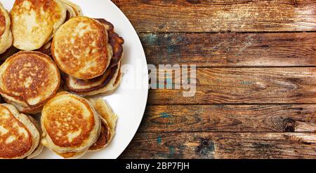 Ein Stapel frisch gebackener Pfannkuchen lag auf einem Teller isoliert auf Holztisch Hintergrund. Draufsicht. Mit Beschneidungspfad. Stockfoto